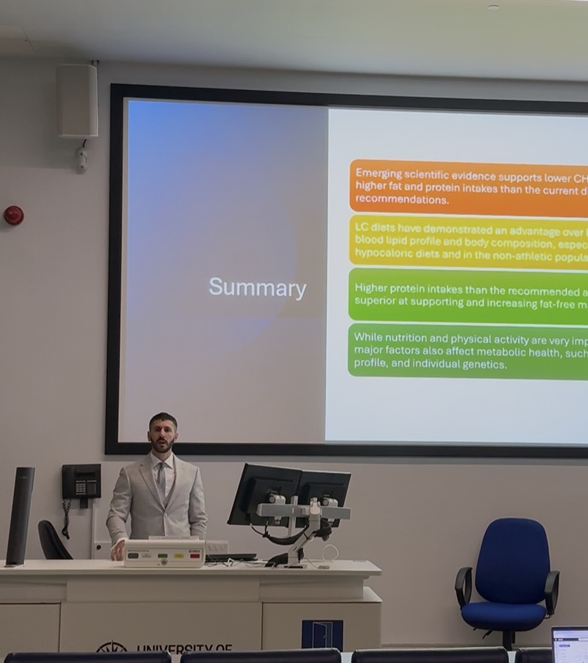 Alexandros presenting research at a conference in his grey suit