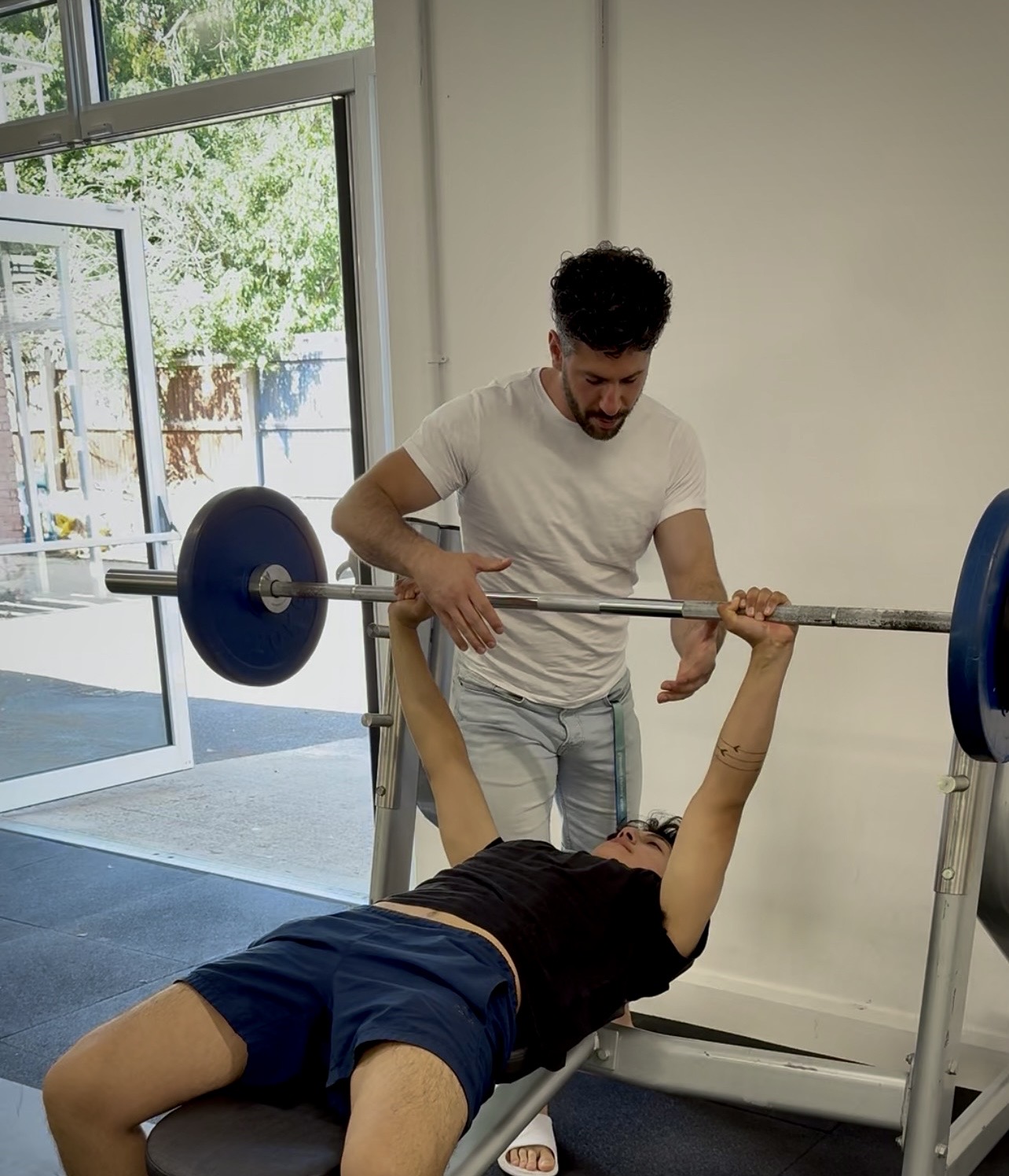 Alexandros coaching a client through a barbell bench press