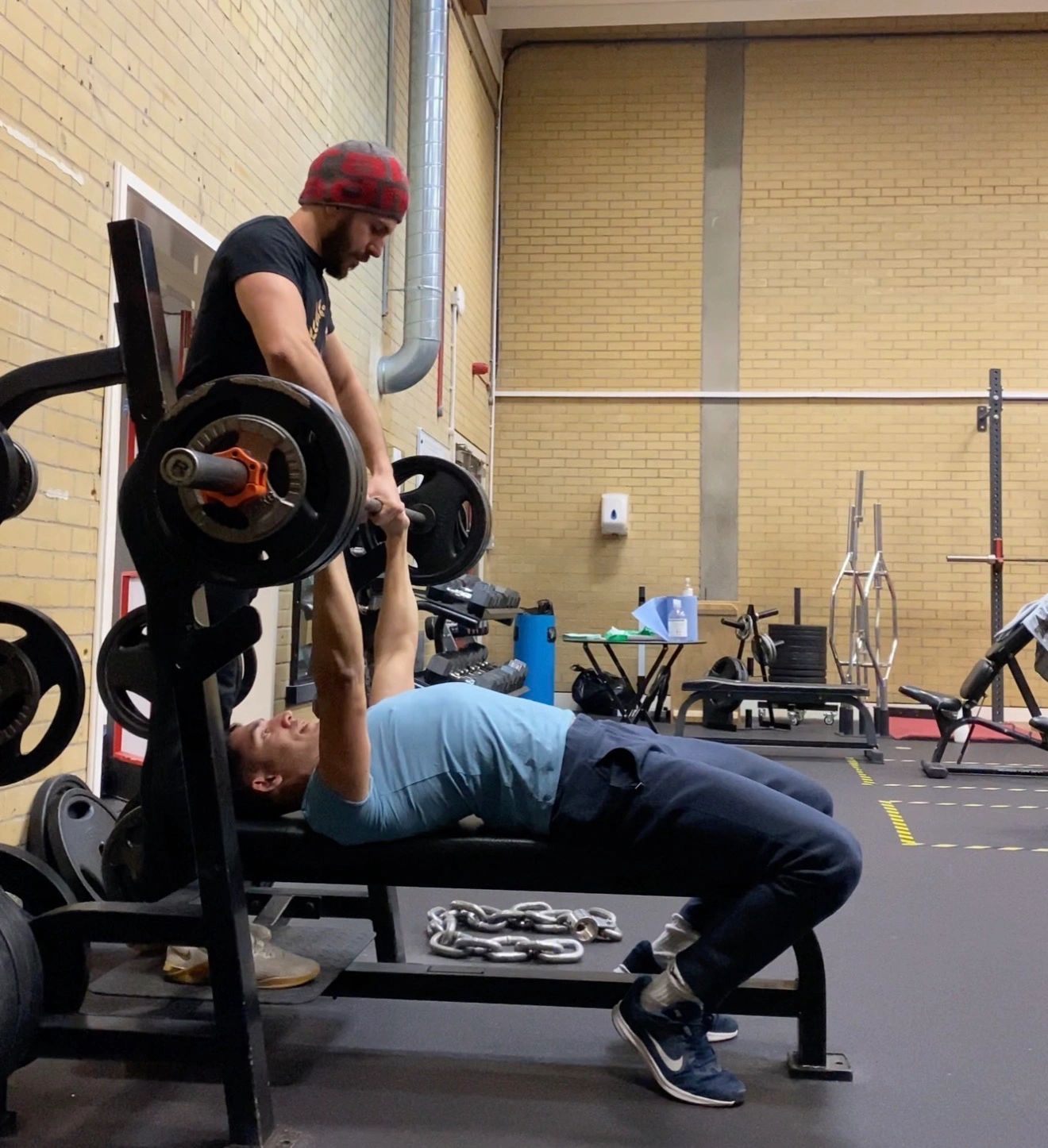 Alexandros spotting a client during a bench press